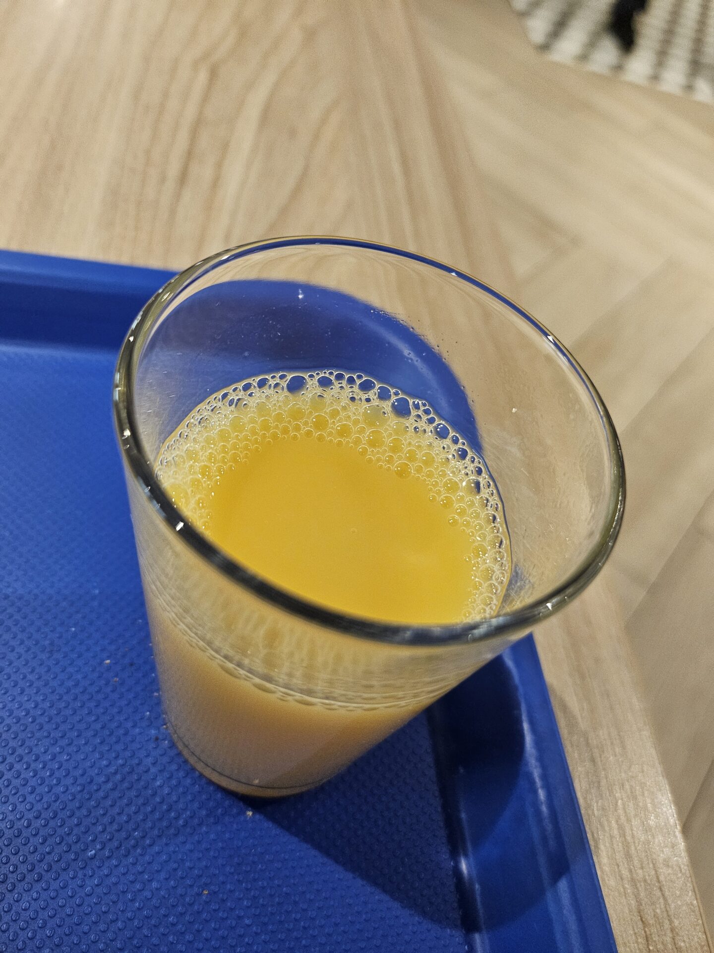 a glass of orange juice on a blue tray