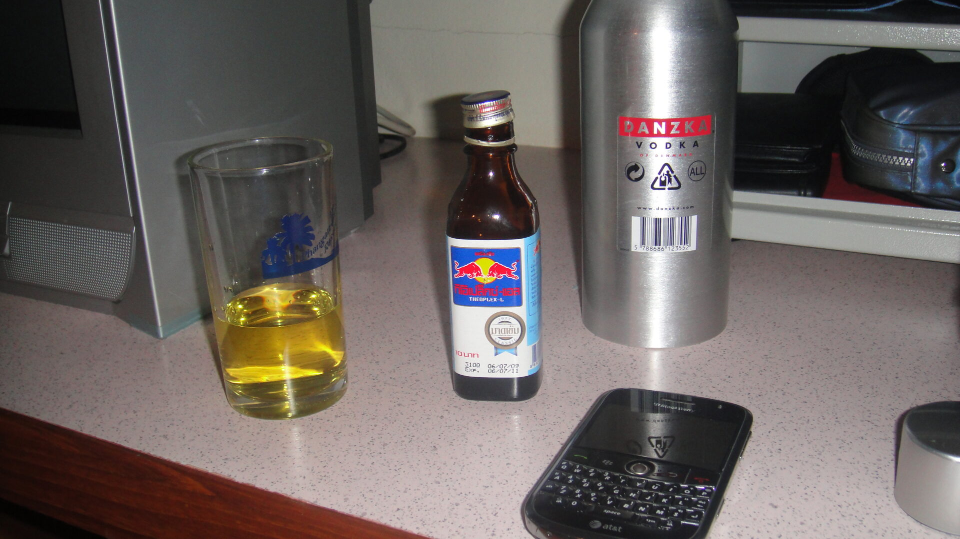 a bottle and a glass of liquid next to a cell phone