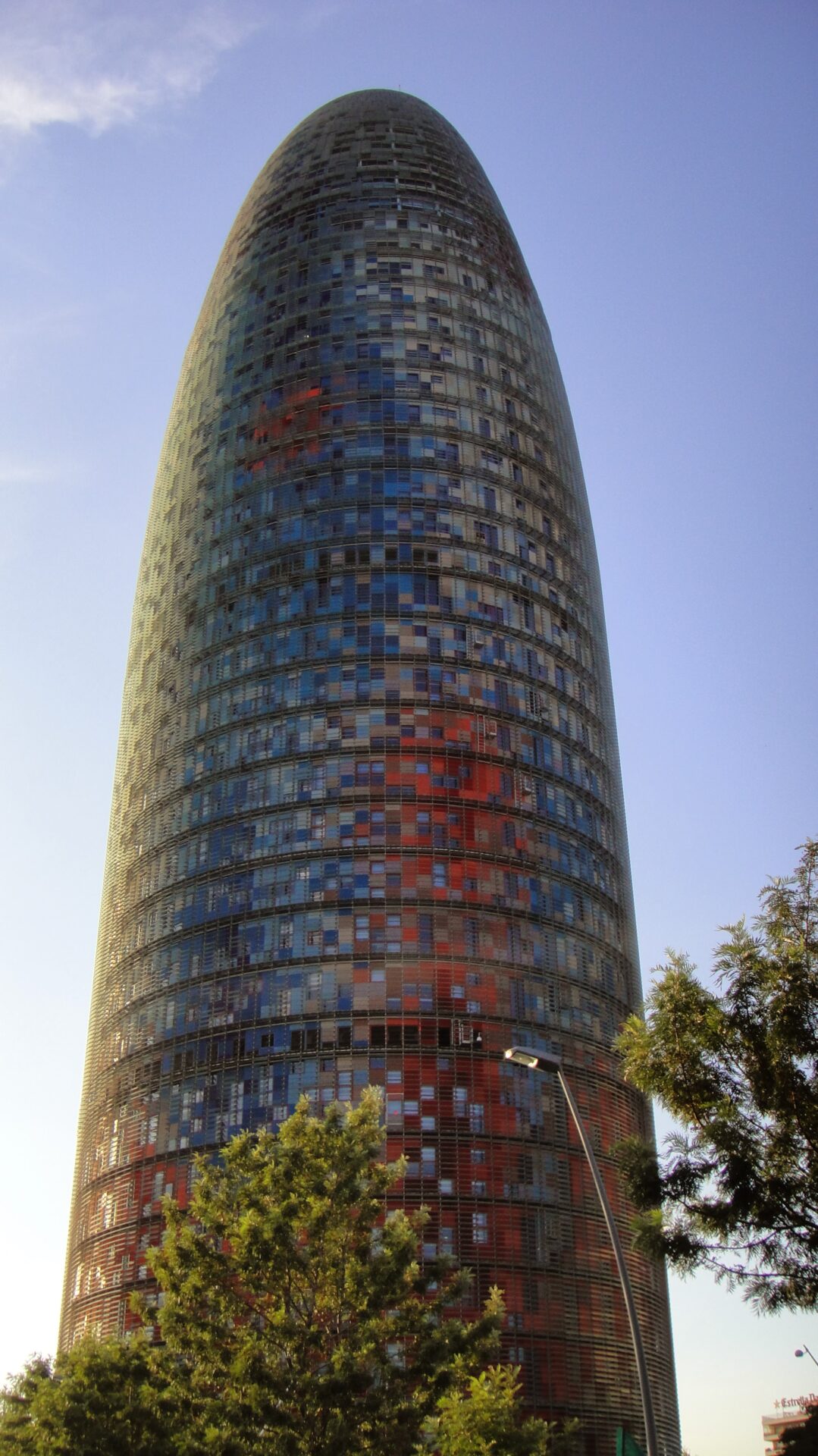 a tall building with many windows with Torre Agbar in the background