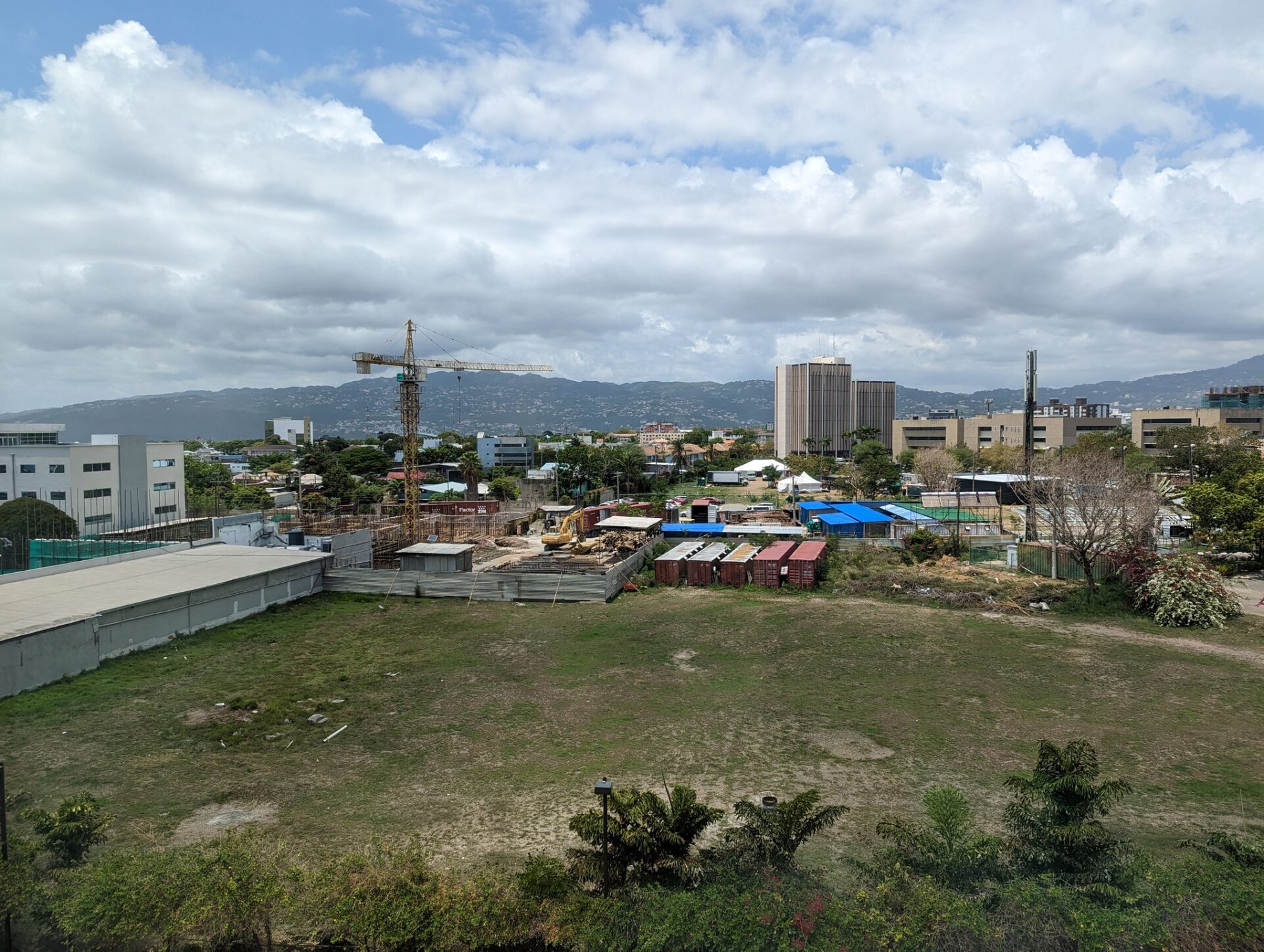 a large field with buildings and a crane in the background