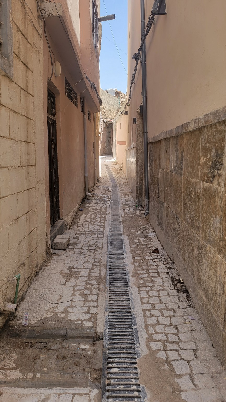 a narrow alleyway with a drain