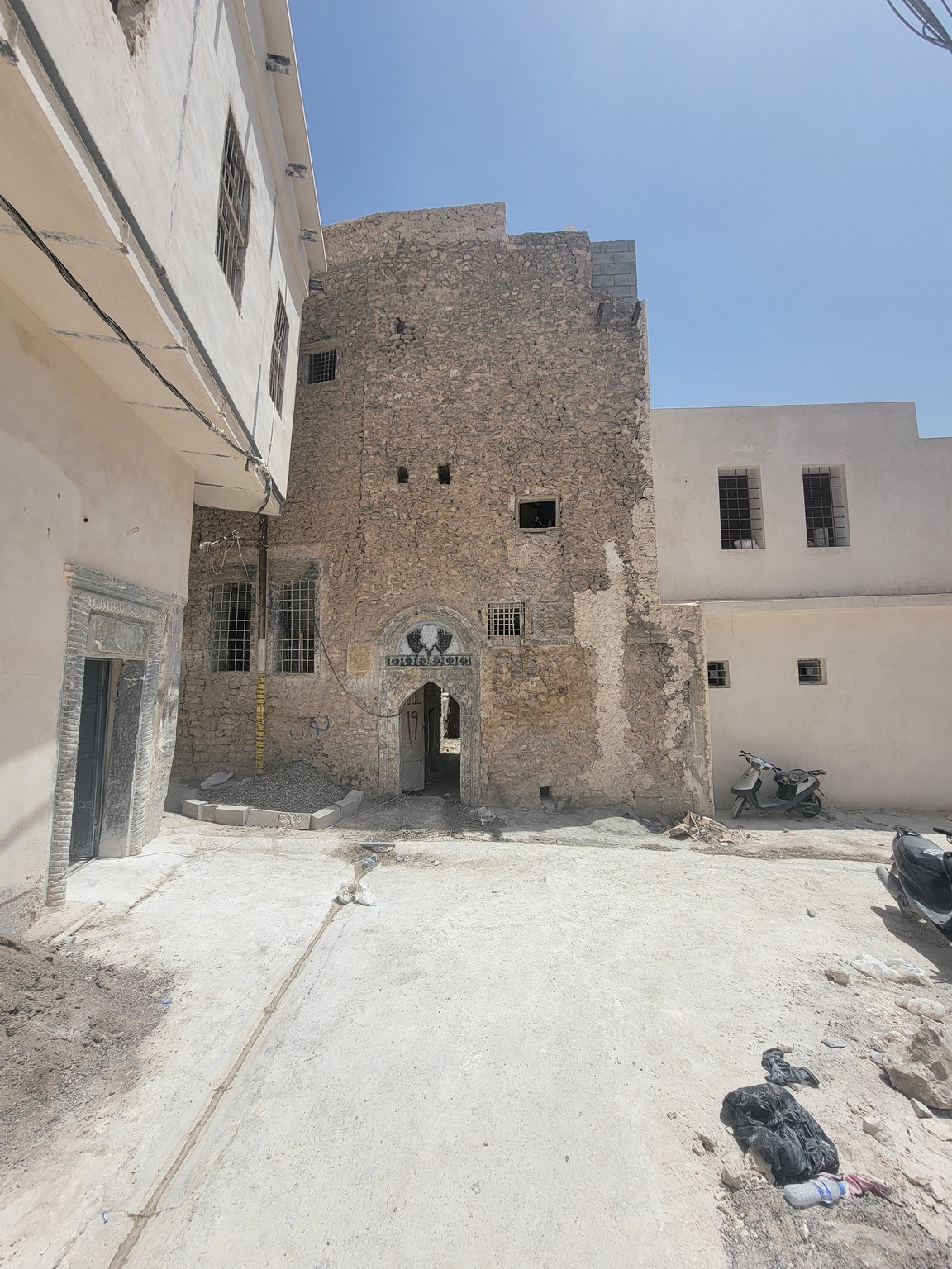 a building with a stone wall and a dirt road