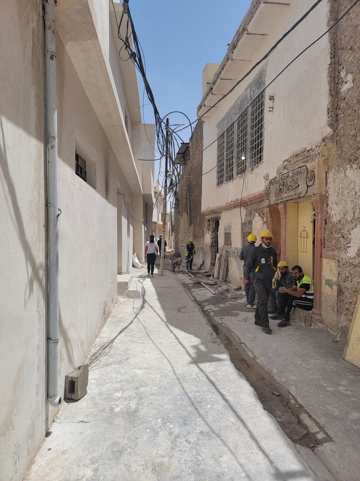 a group of people in hardhats standing in a narrow alley