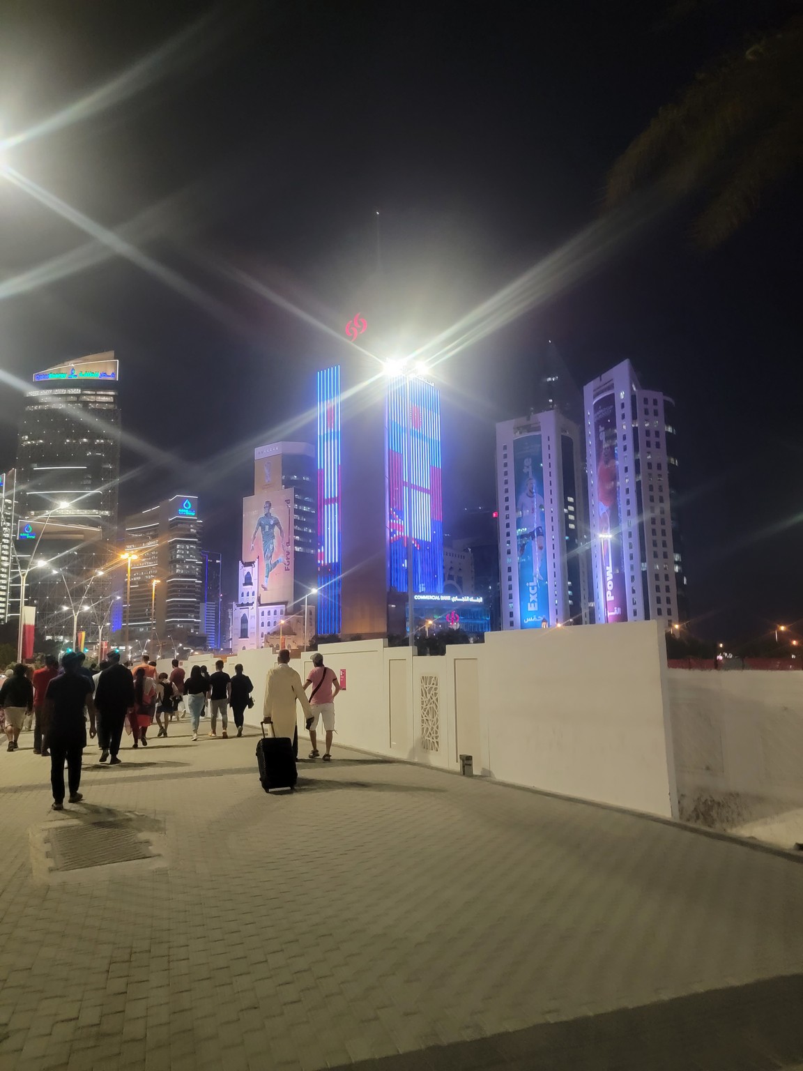 a group of people walking on a sidewalk with lights