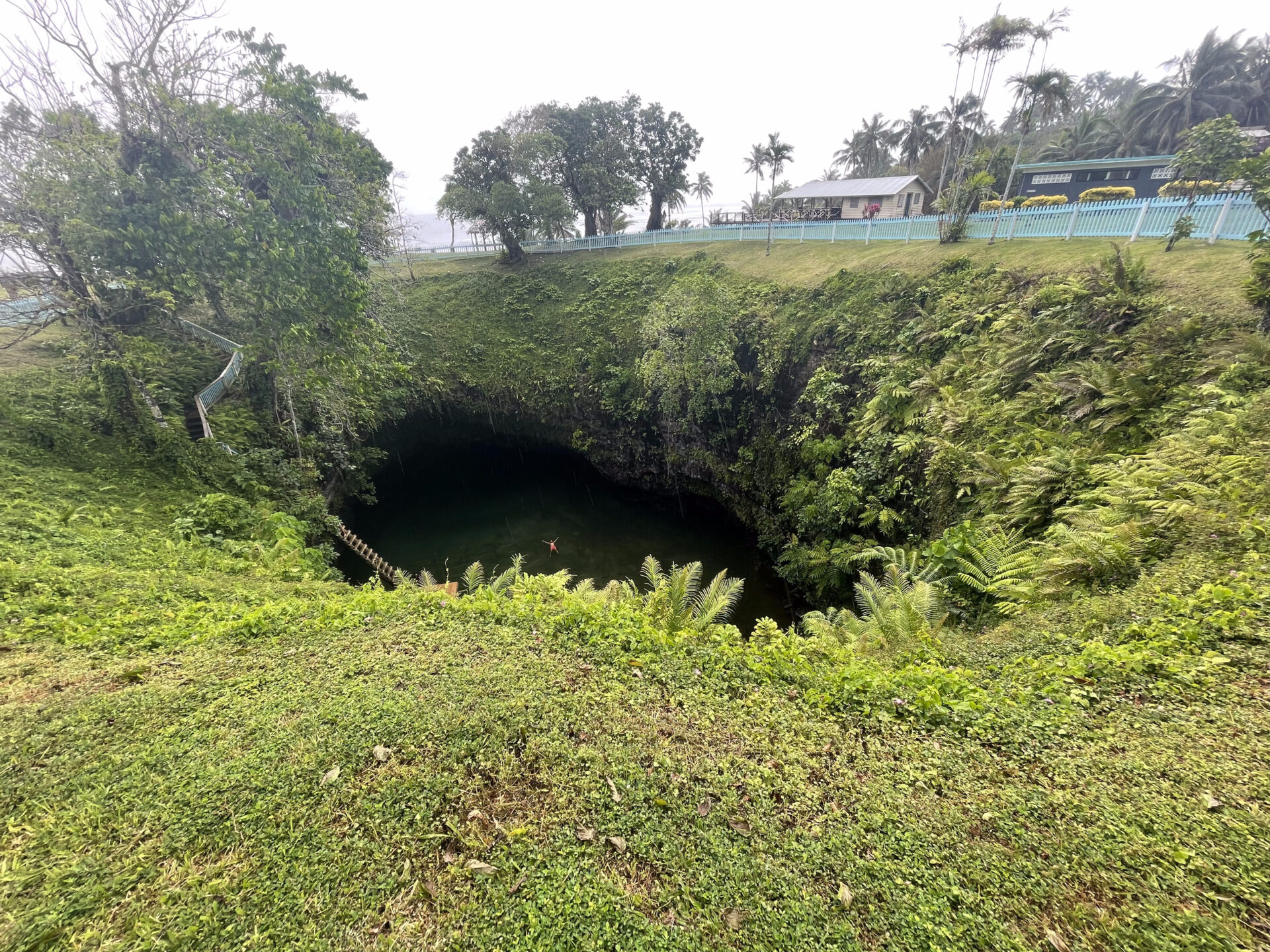 a hole in the ground with trees and a building in the background