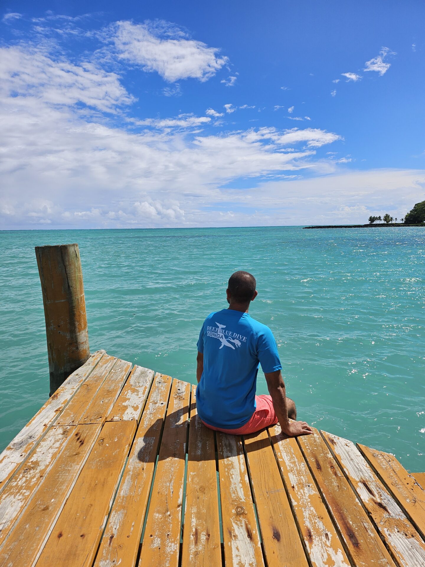 a man sitting on a dock looking out to the ocean