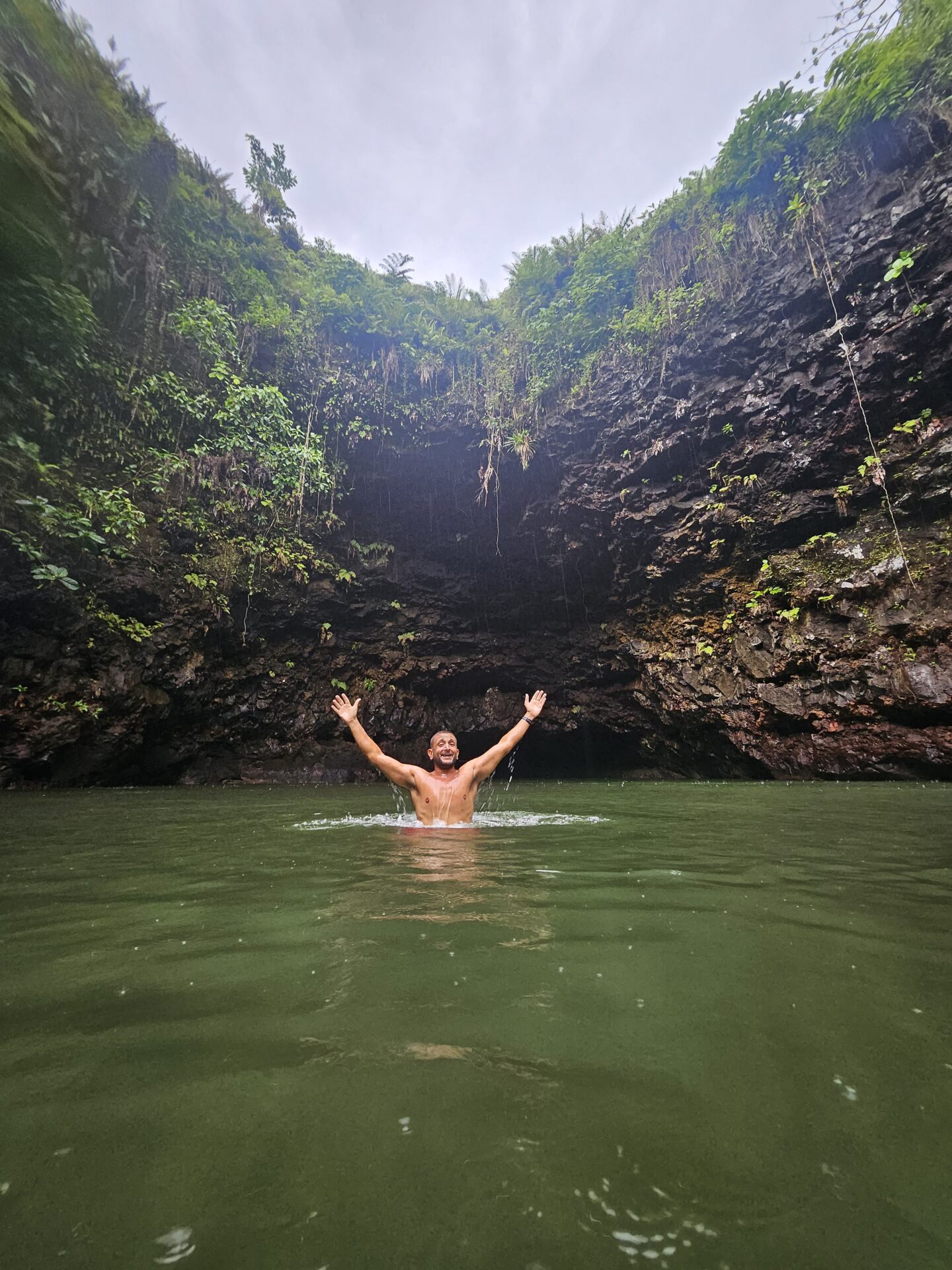 a man in a body of water with his arms raised