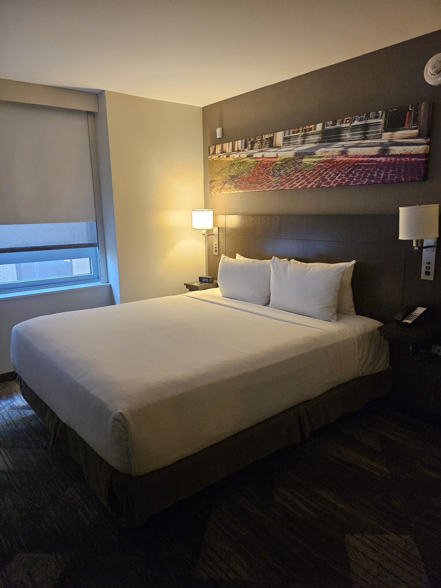 a bed with white sheets and lamps in a hotel room