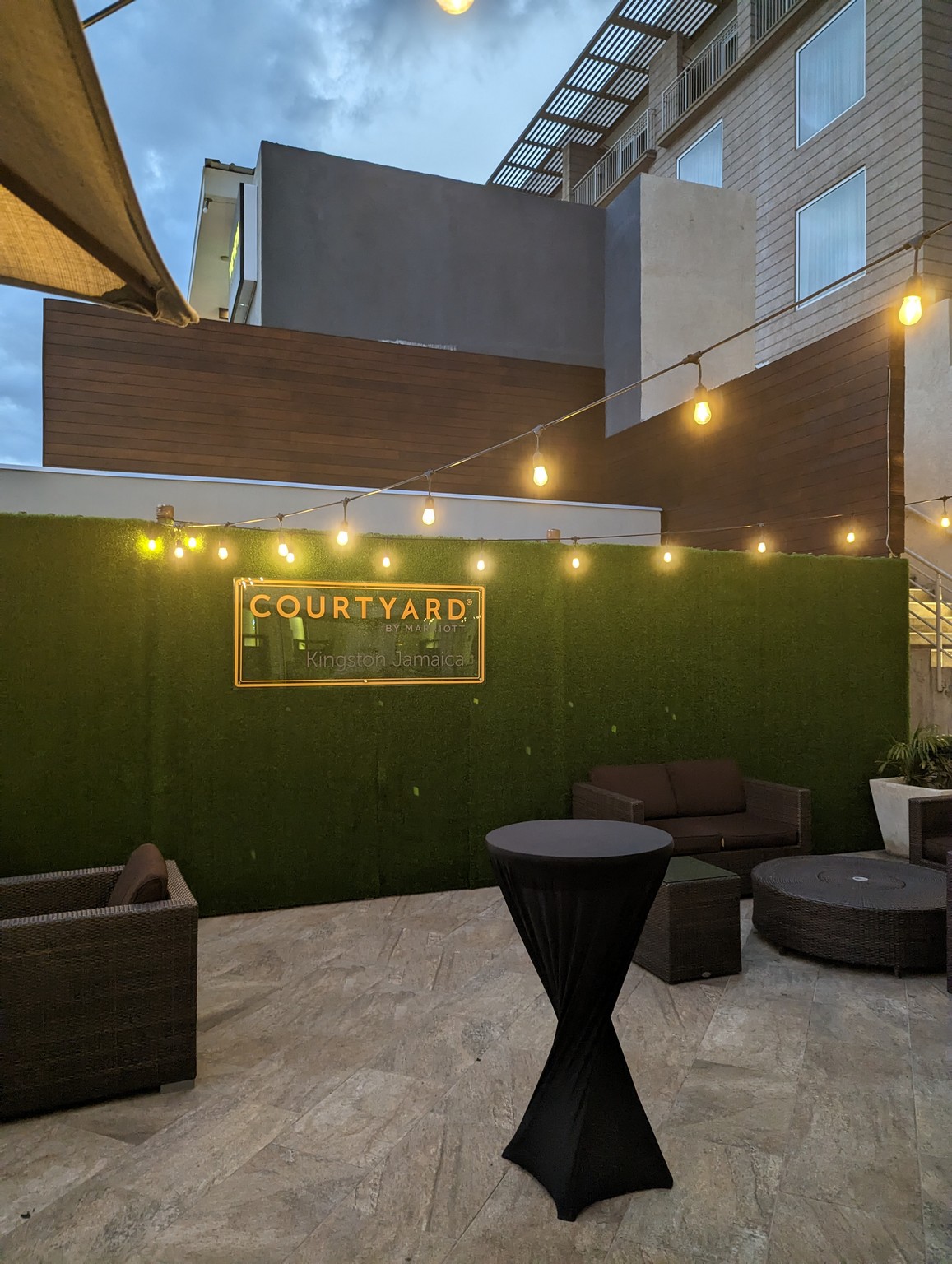 a patio with a green wall and a table and chairs