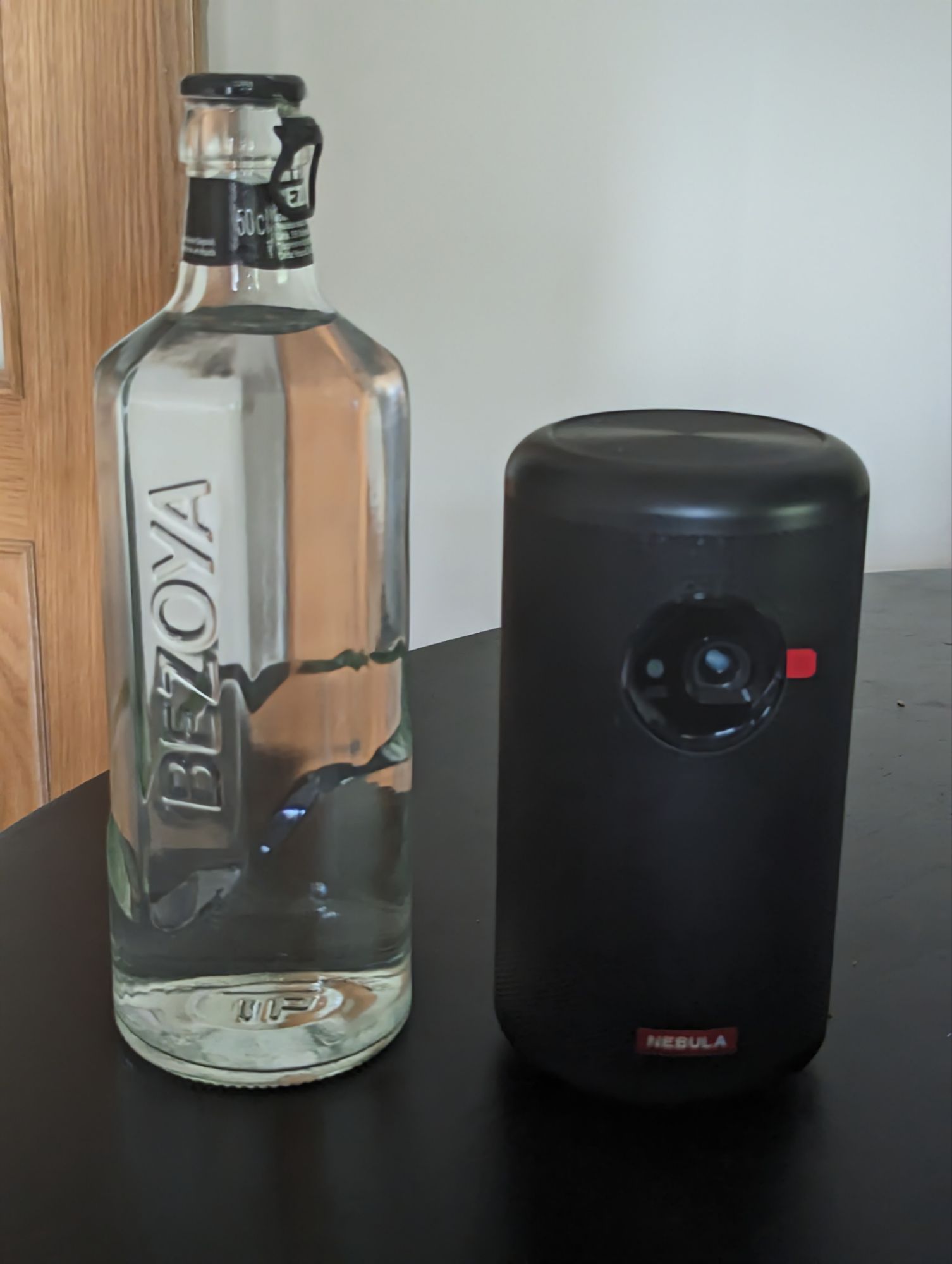 a glass bottle next to a black cylinder