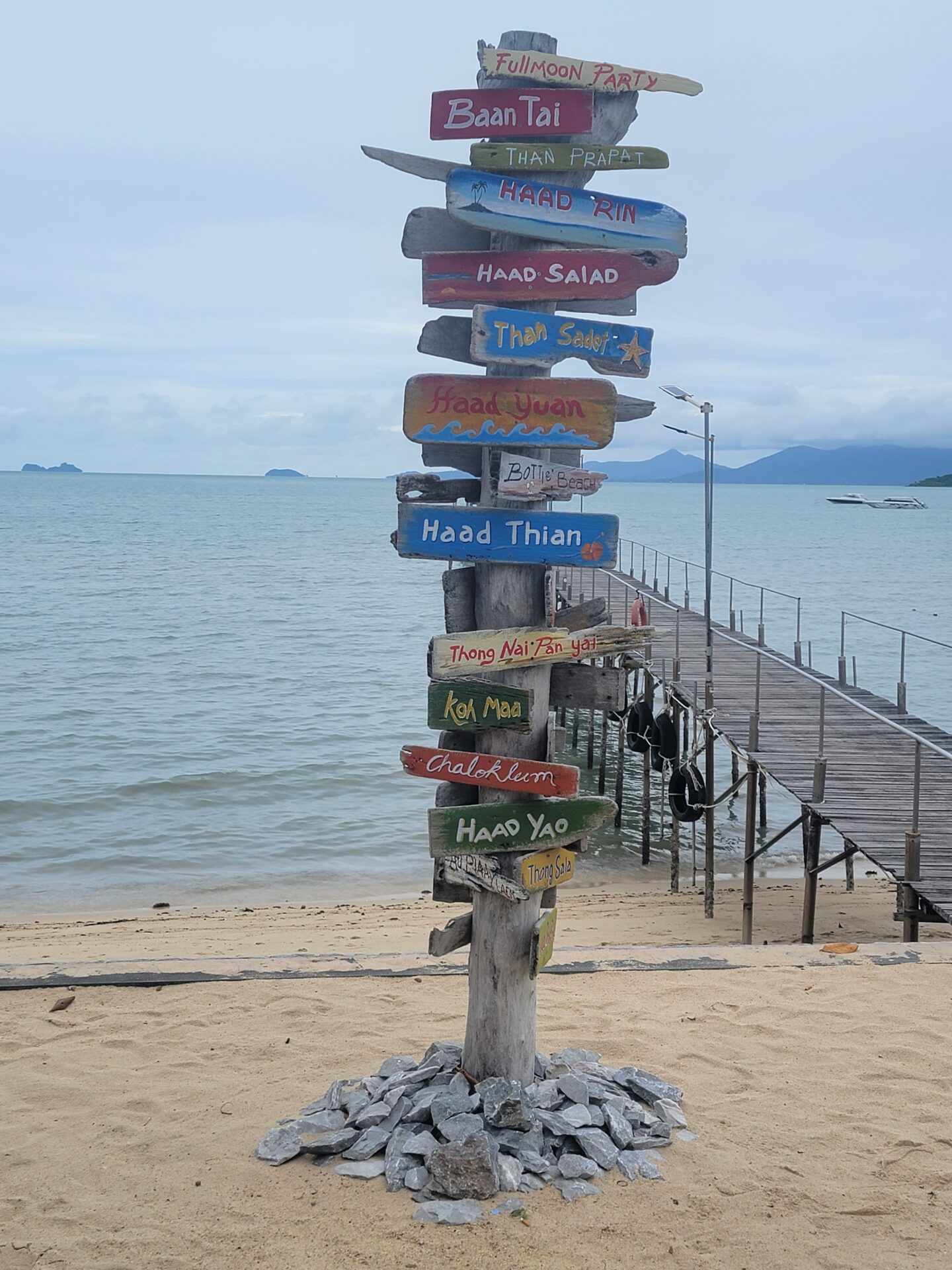 a sign post with many different colored signs on a beach