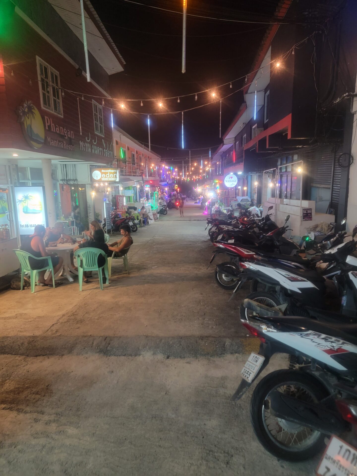 a street with motorcycles and people sitting at tables