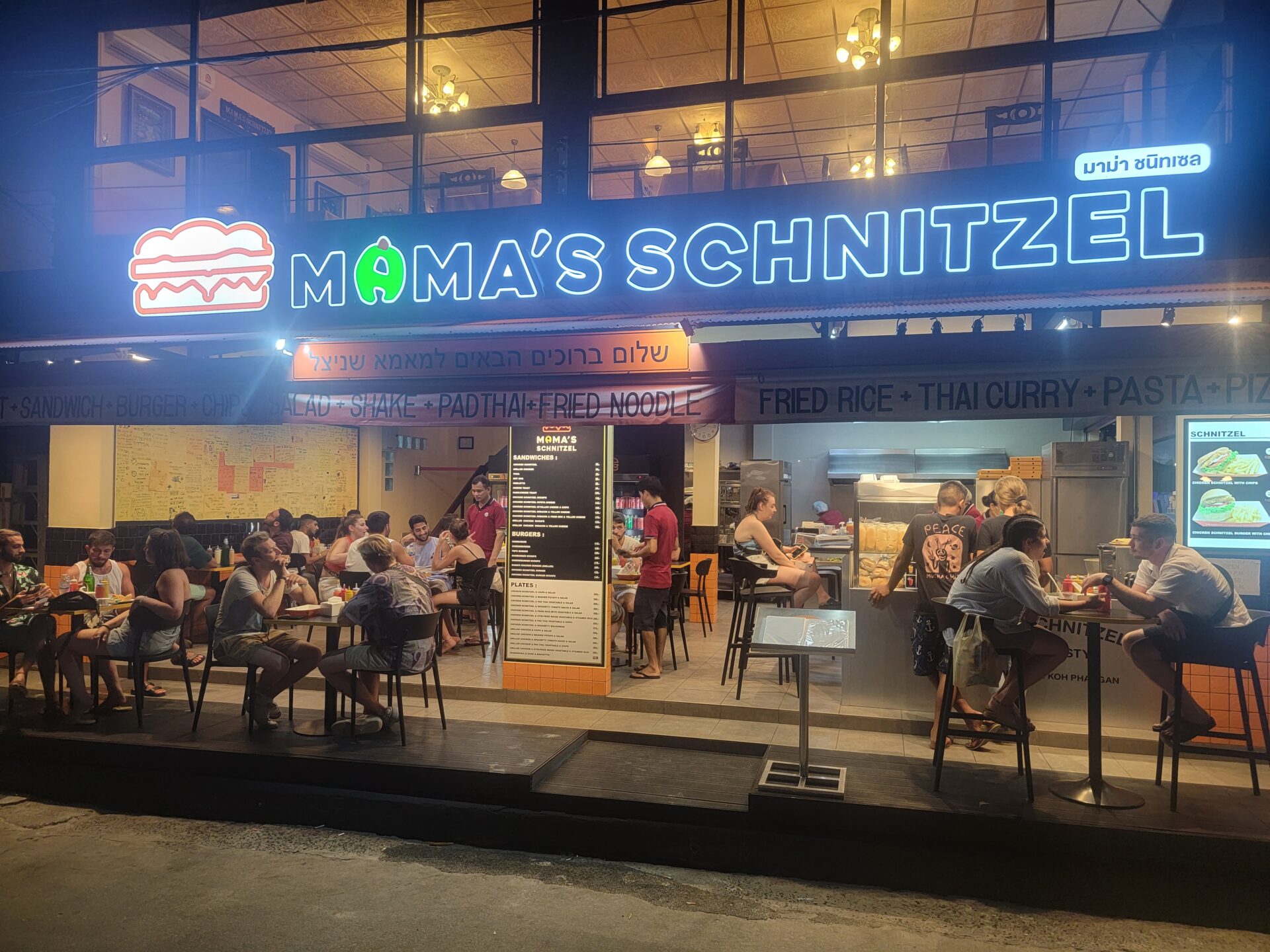 a group of people sitting at tables outside a restaurant