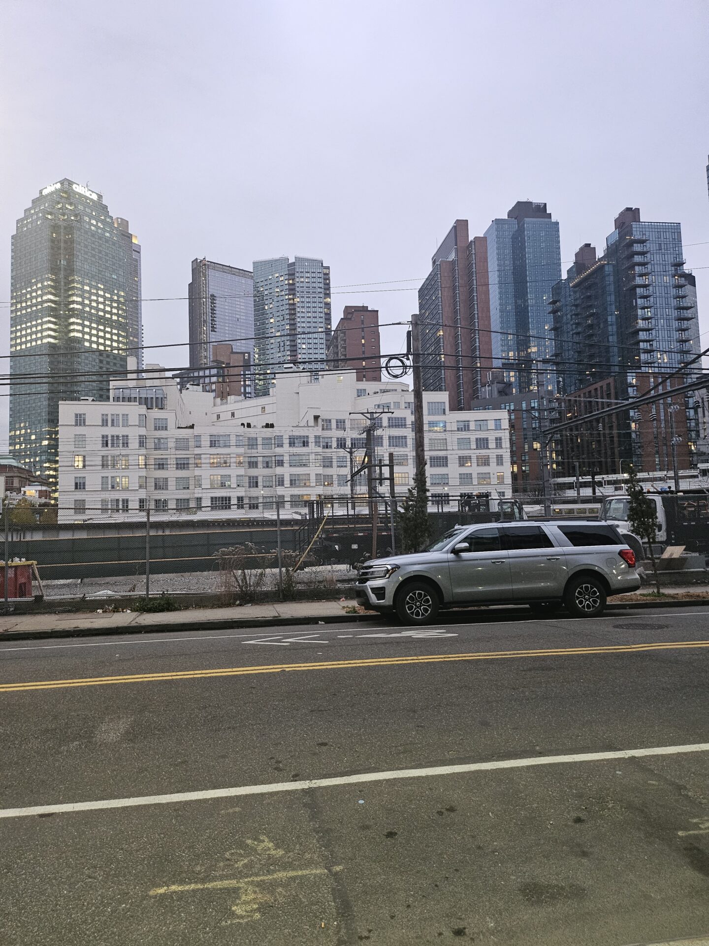 a car parked on the side of a road with a city skyline behind it