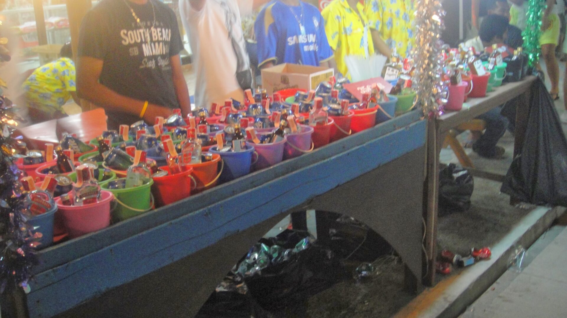 a group of people standing next to a table with buckets of alcohol