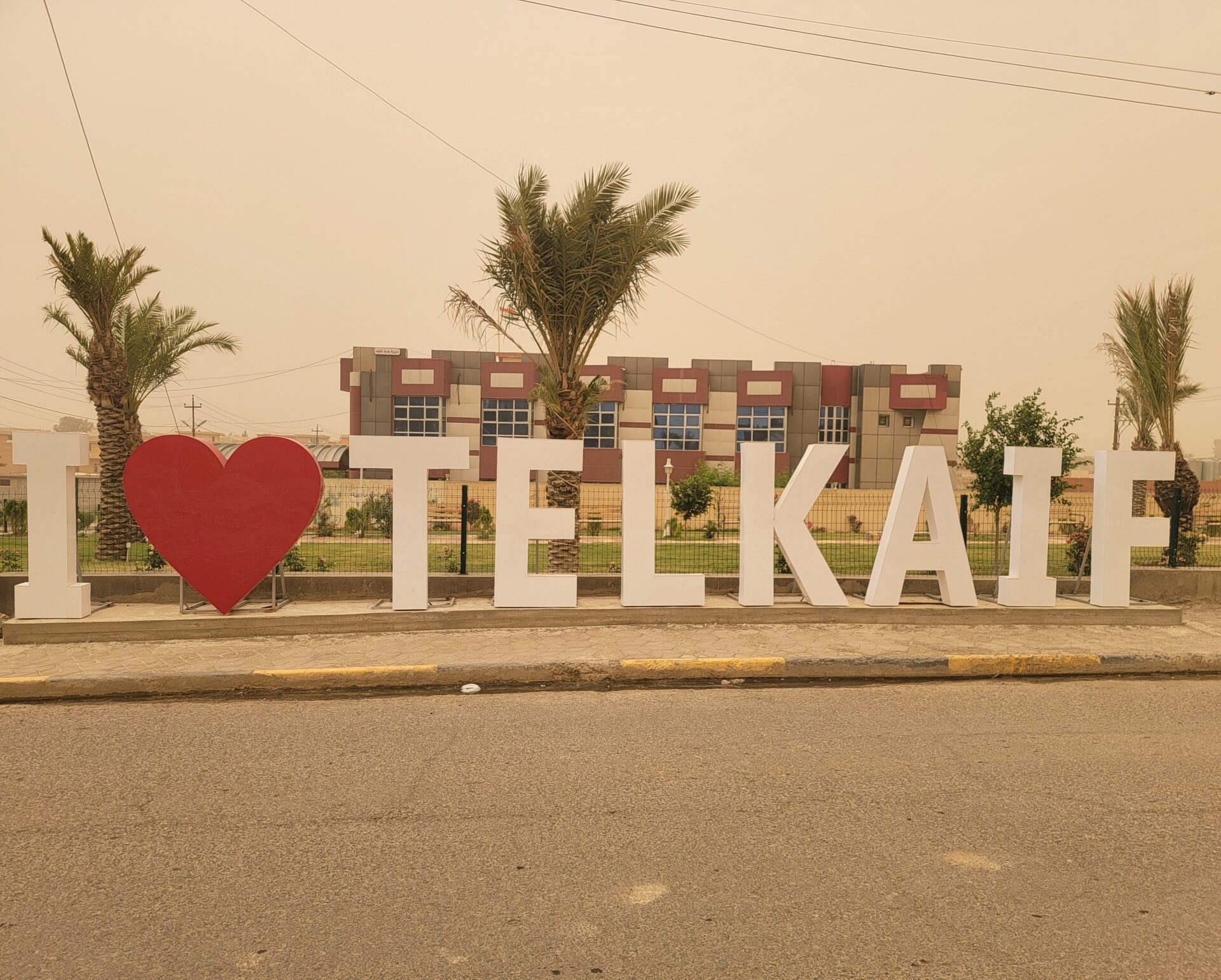 a large white letters with a heart on the side of a road