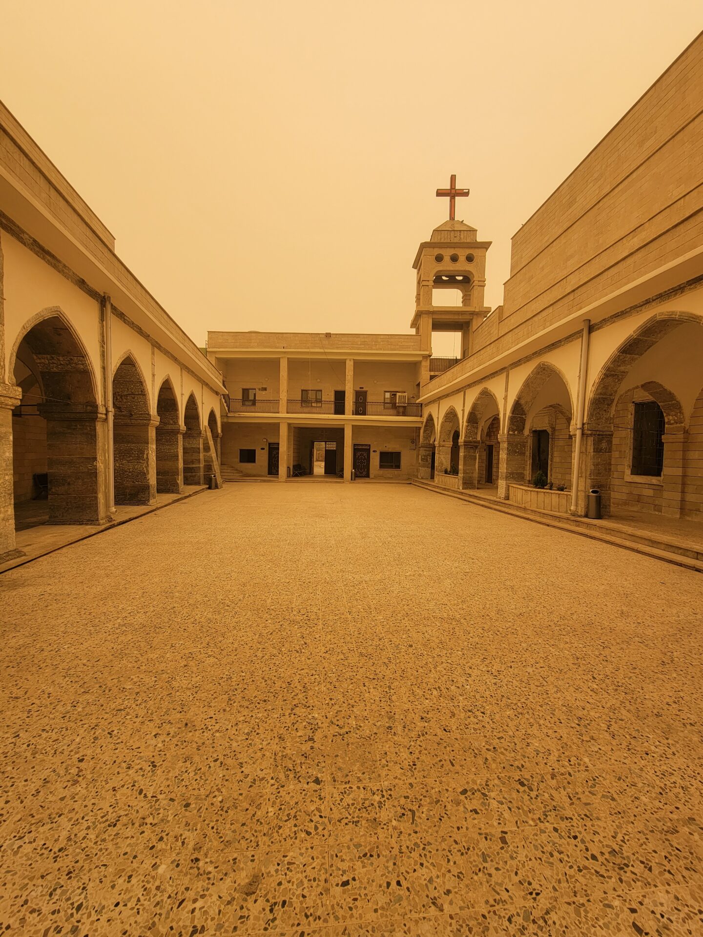 a courtyard with arches and a cross on top