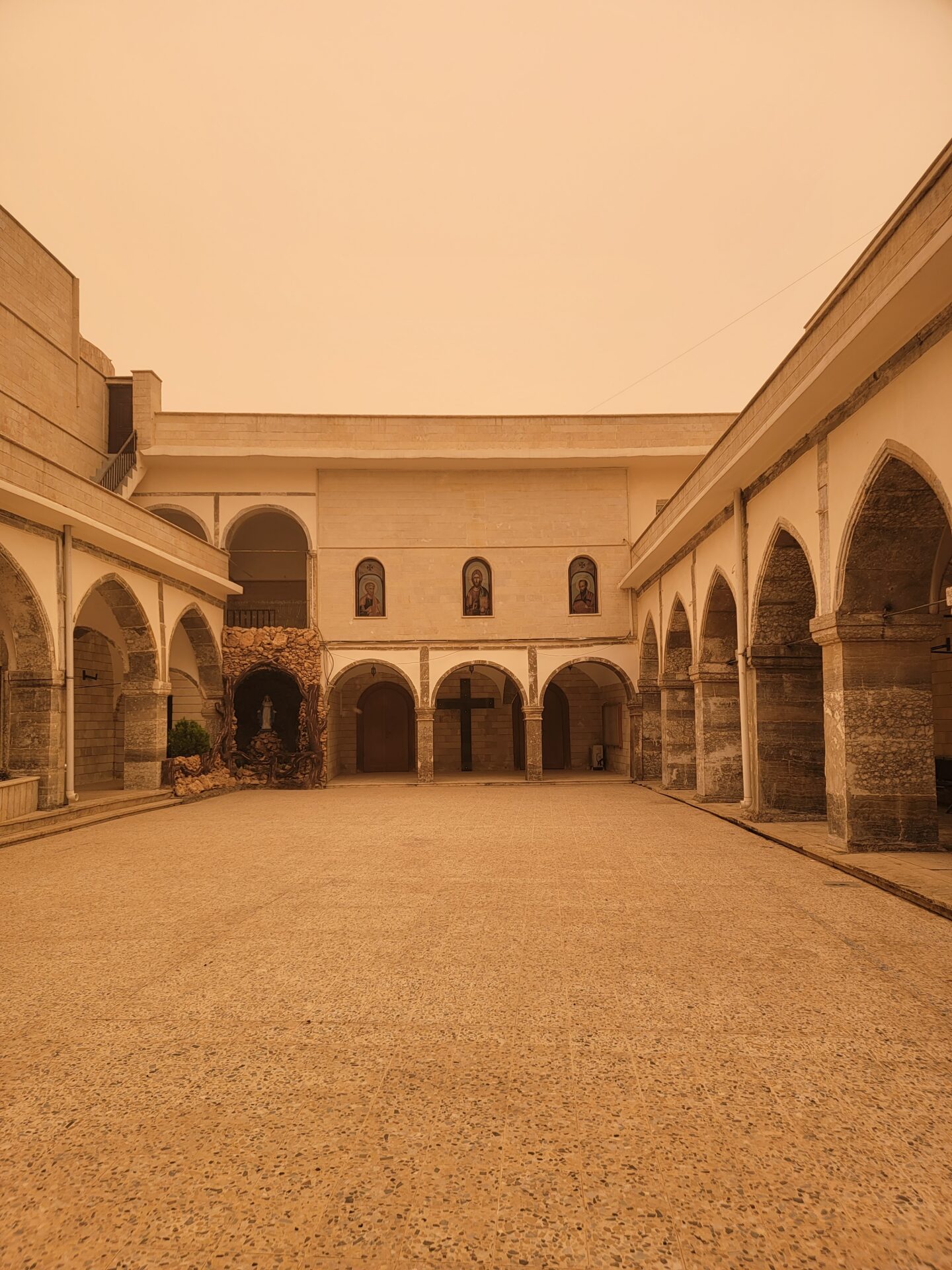 a courtyard with arches and a stone building