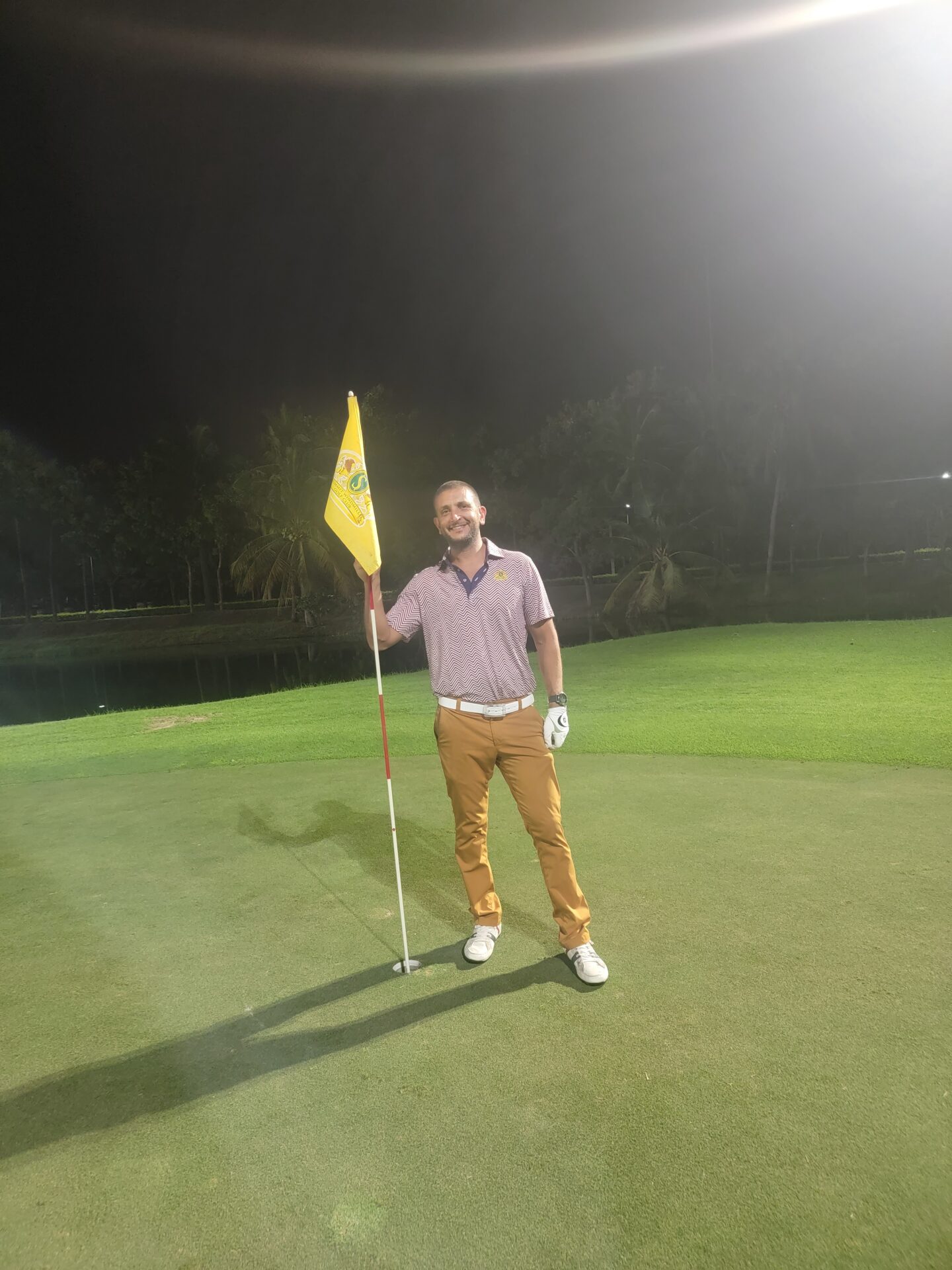 a man holding a flag on a golf course