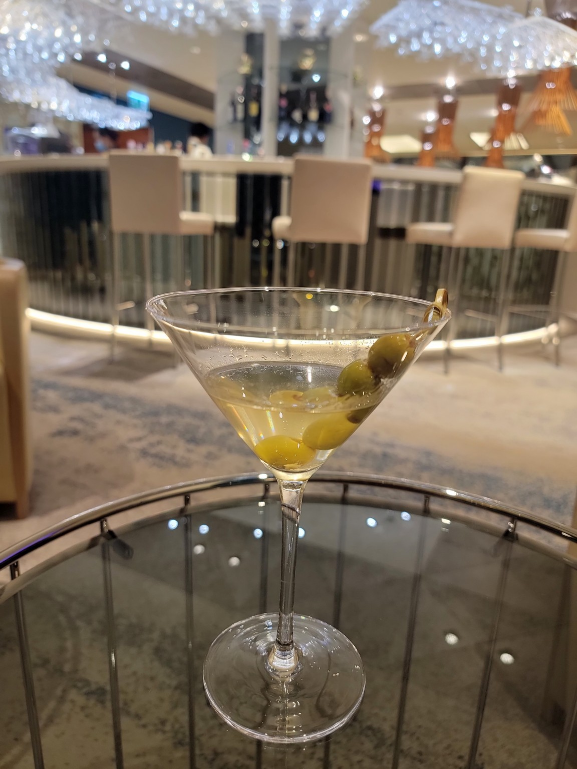 a martini glass with olives on a table