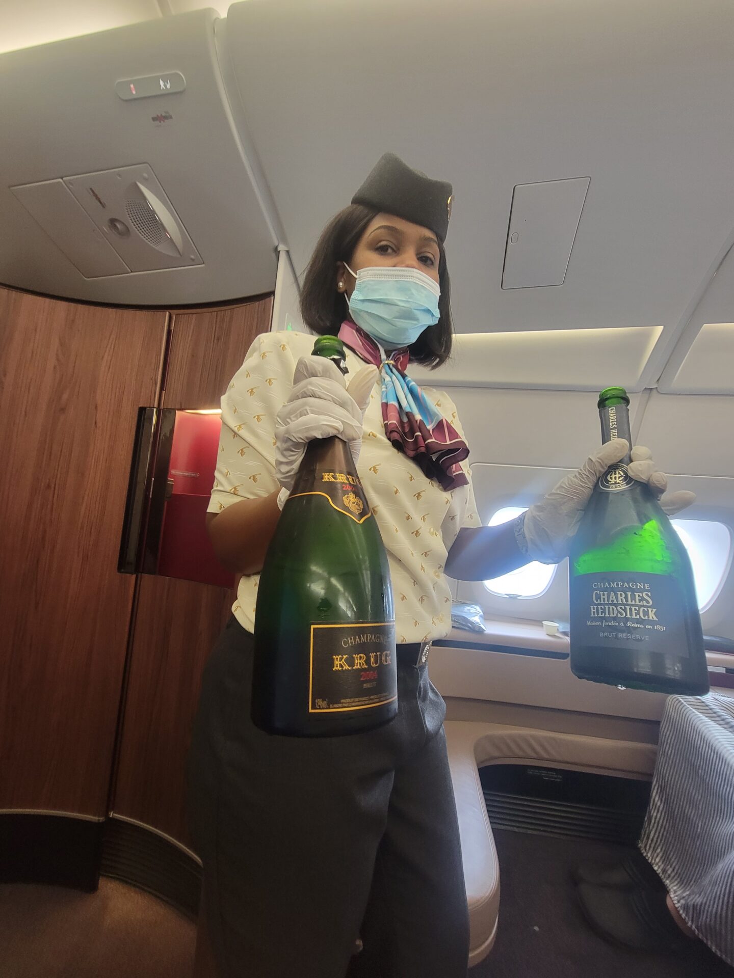 a woman wearing a mask and gloves holding two bottles of champagne