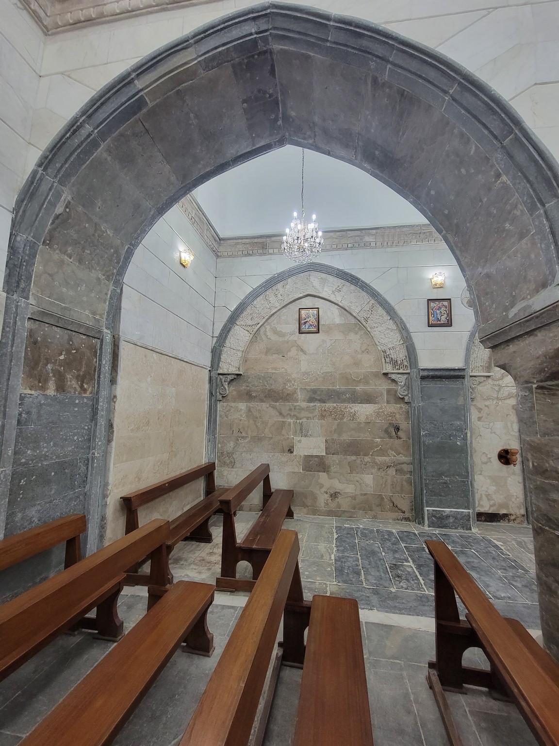 a stone archway with benches and a chandelier