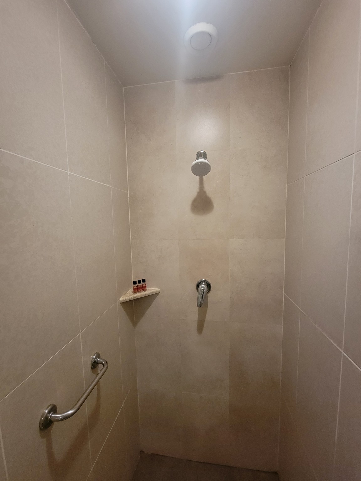 a shower with a shower head and a shelf