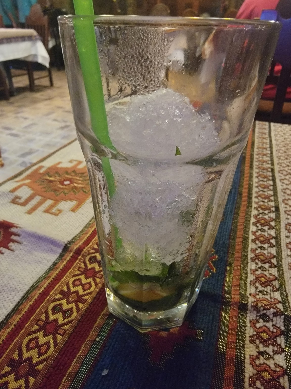 a glass with ice and a straw on a table