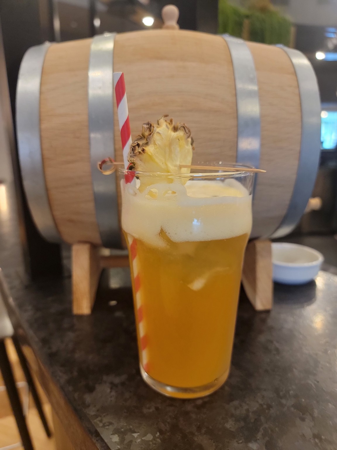 a glass of beer with a straw and pineapple on a table