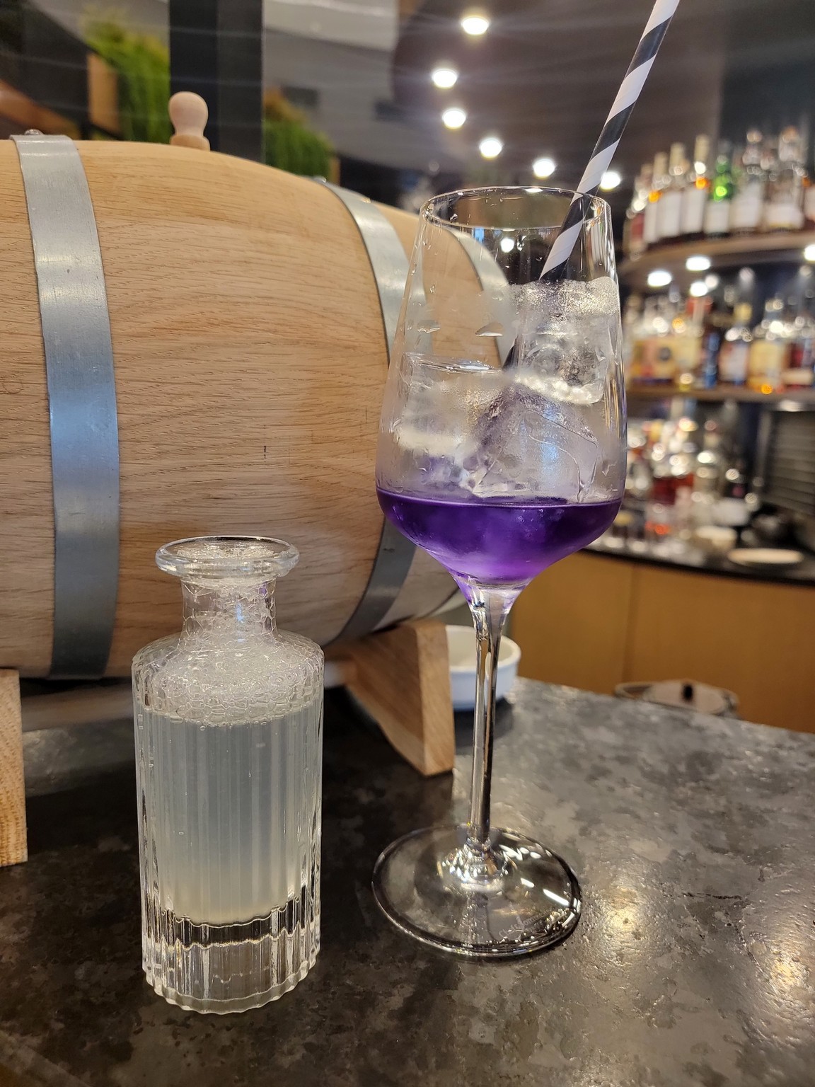 a glass of purple liquid next to a bottle of liquid