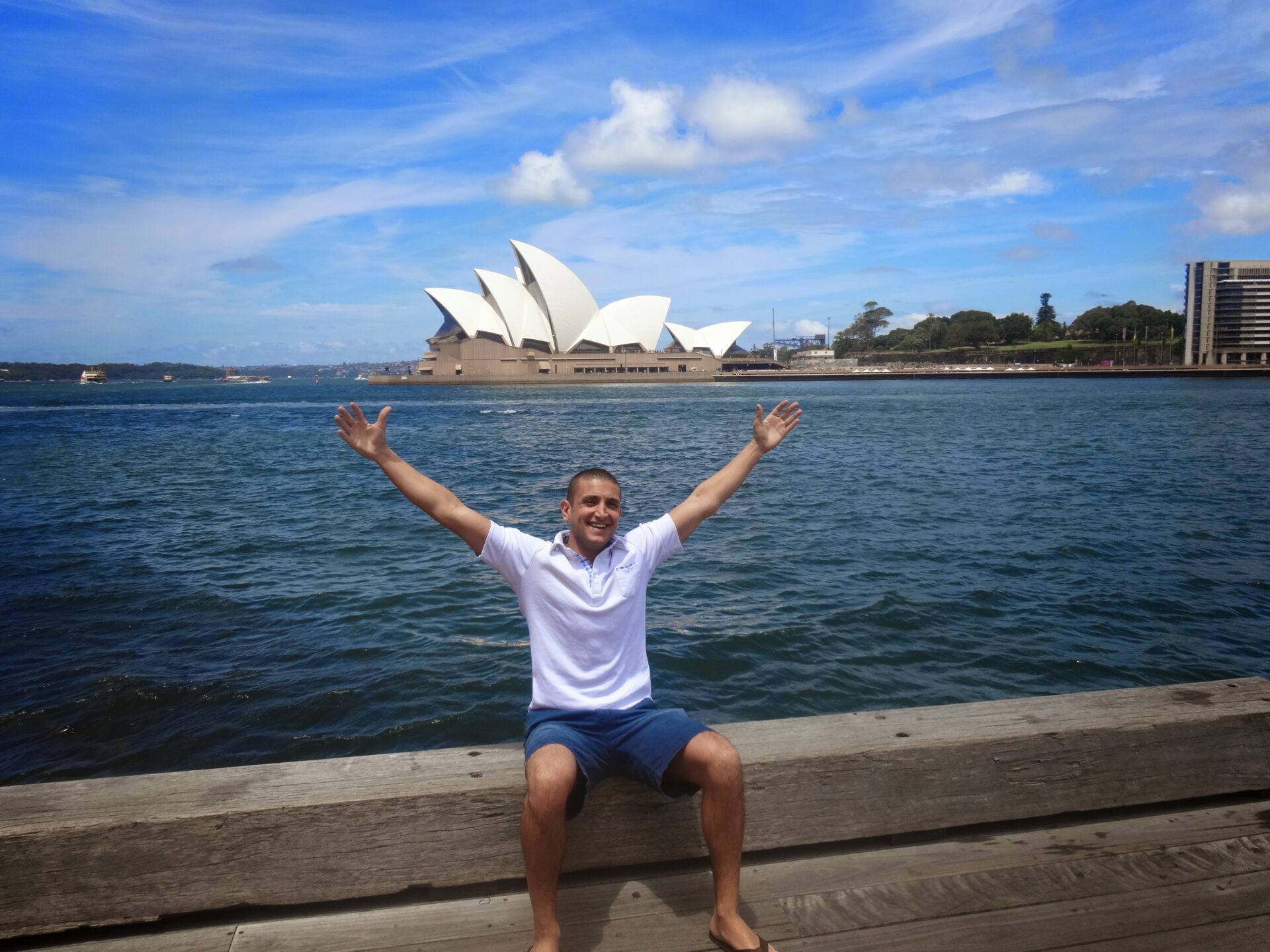 a man sitting on a dock with his arms up in the air