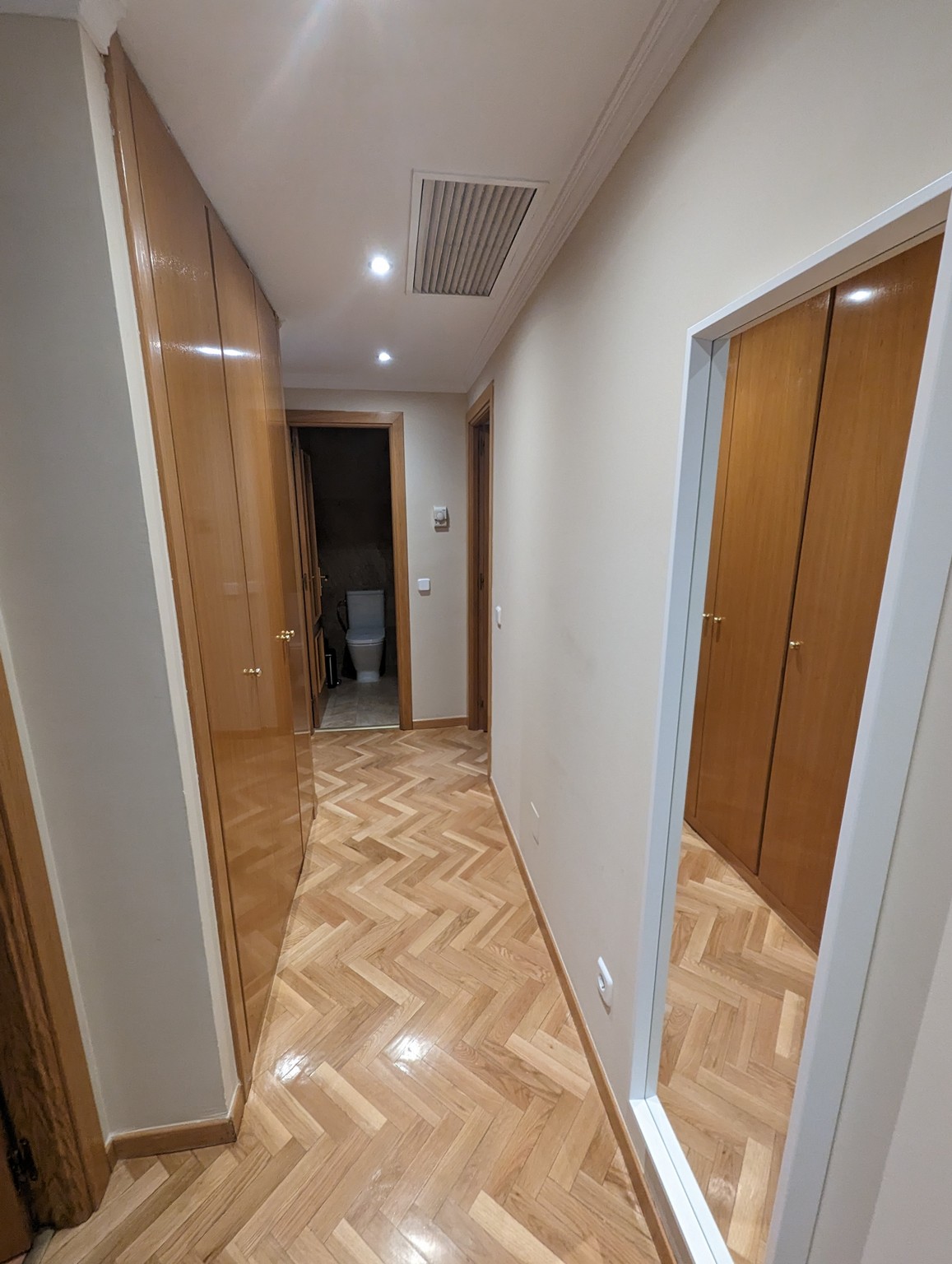 a hallway with wood doors and a toilet