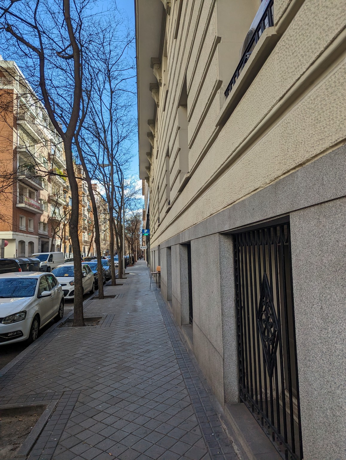 a sidewalk with cars parked on the side of a building