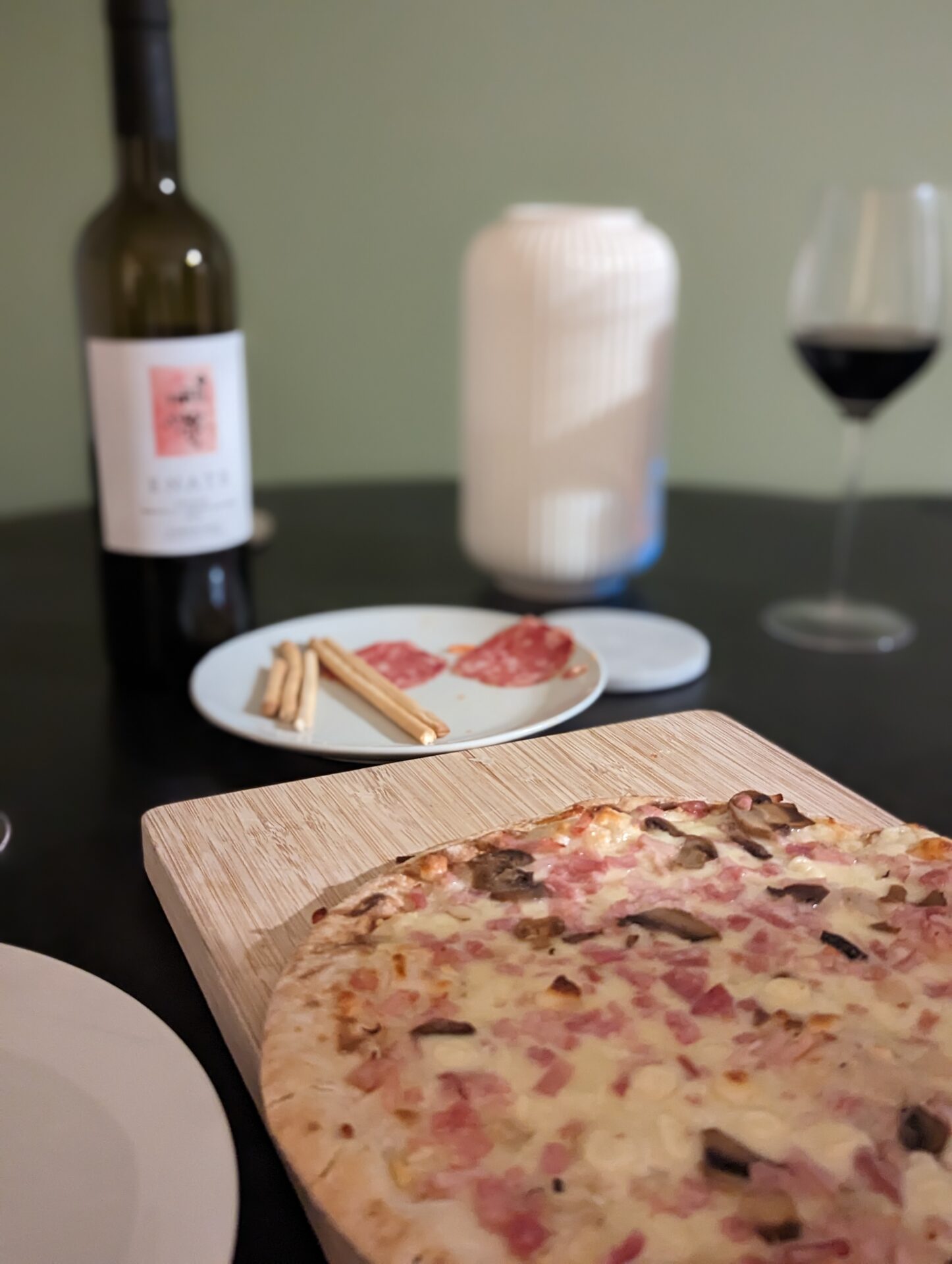 a pizza on a cutting board next to a bottle of wine