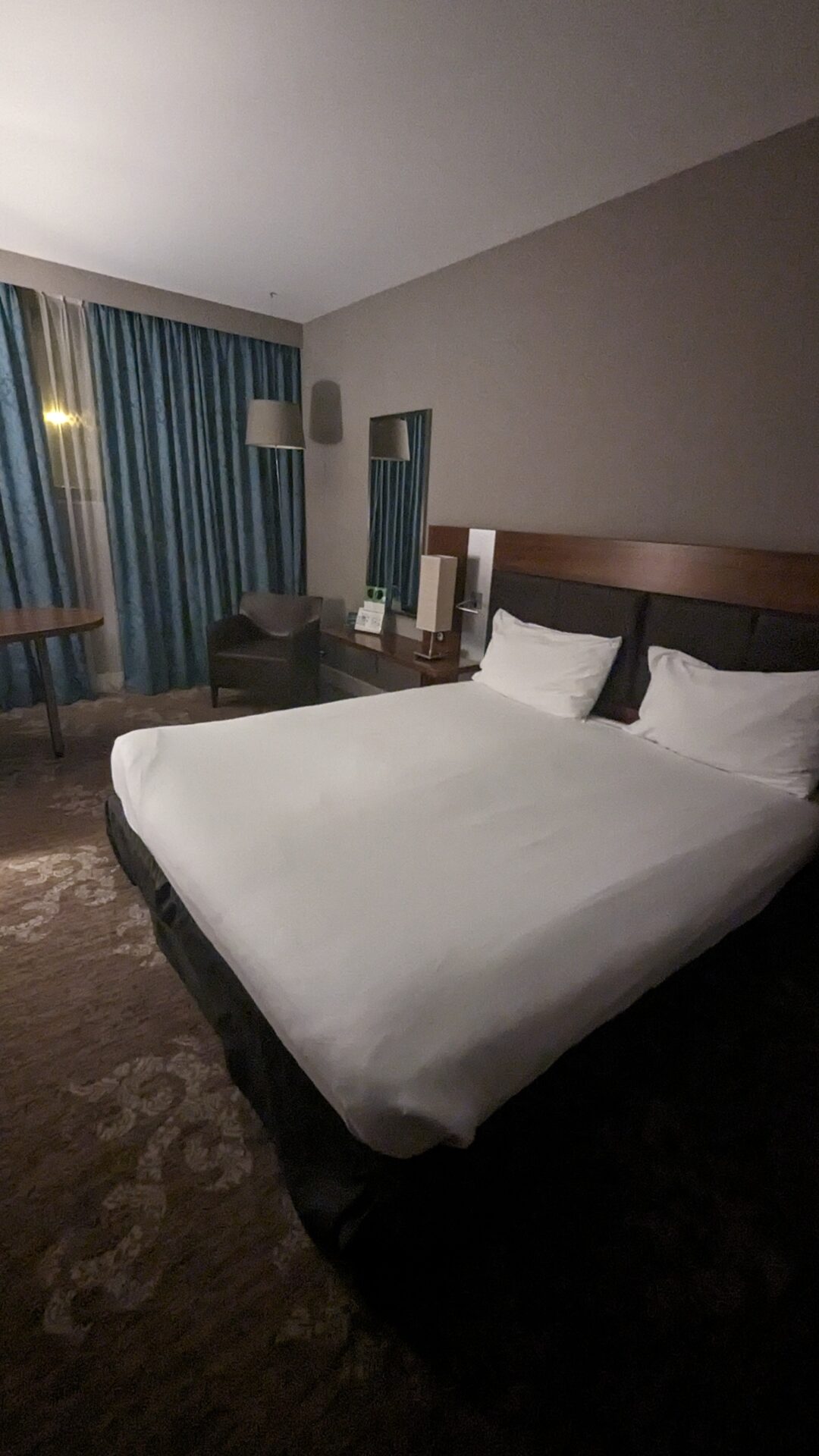 a bed with white sheets and a chair in a room