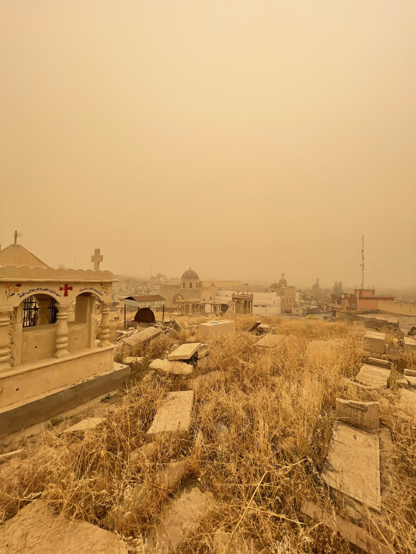 a cemetery with a few buildings and a foggy sky