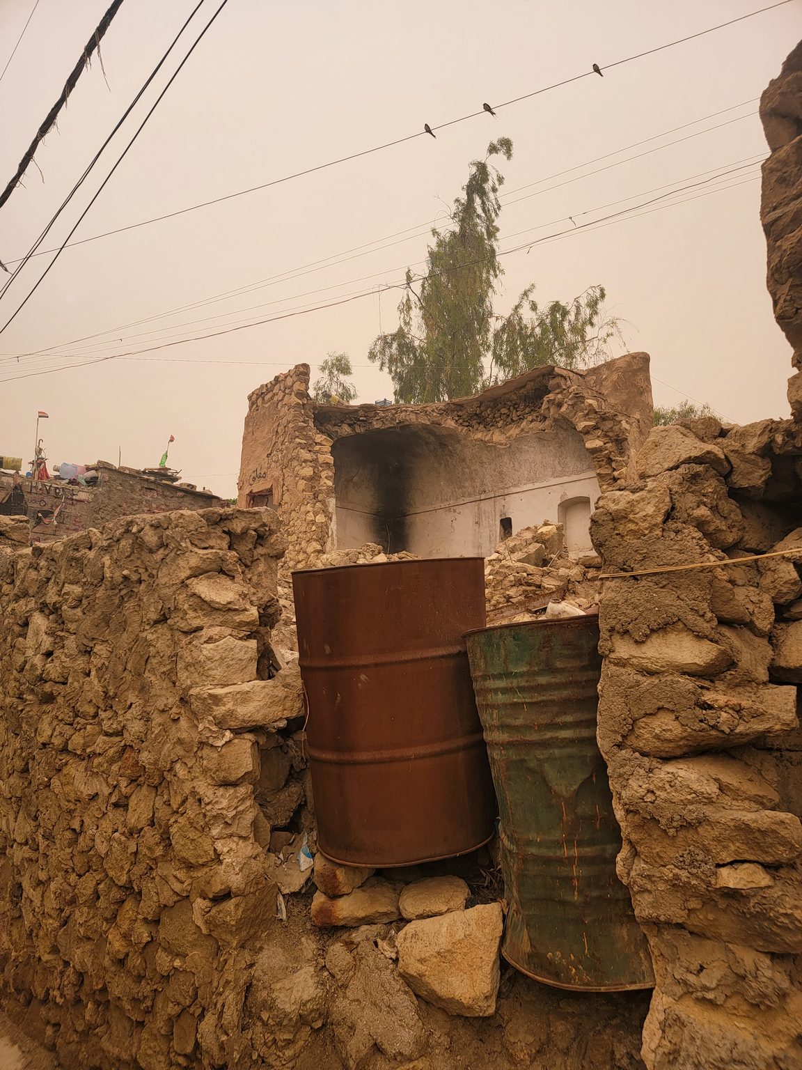 a rusty barrel next to a stone wall