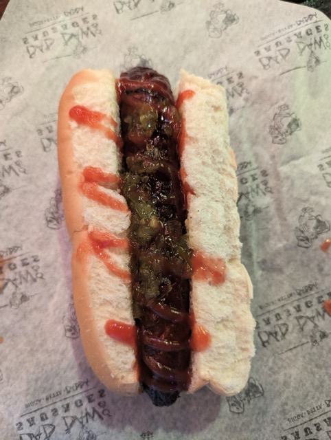 a hot dog with ketchup and onions on a paper