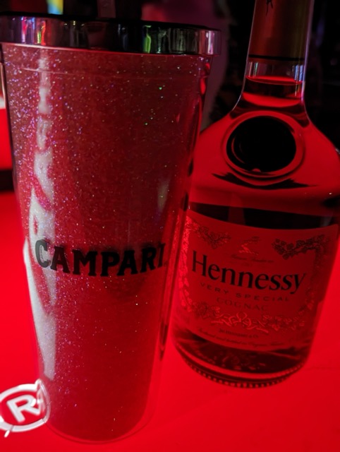 a glass of liquid next to a bottle of alcohol