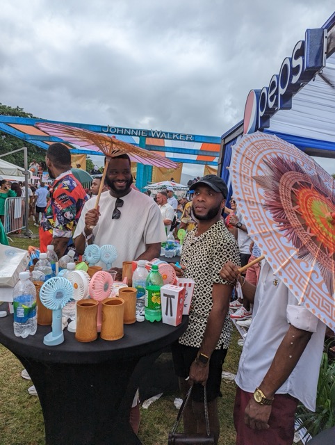 a group of people standing next to a table with umbrellas