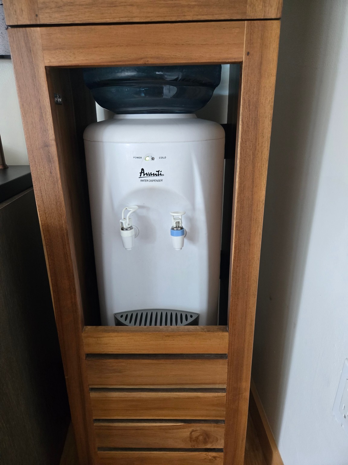 a water cooler in a wood cabinet