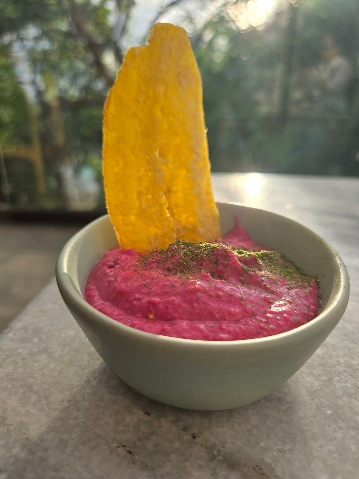 a bowl of pink dip with a potato chip on top