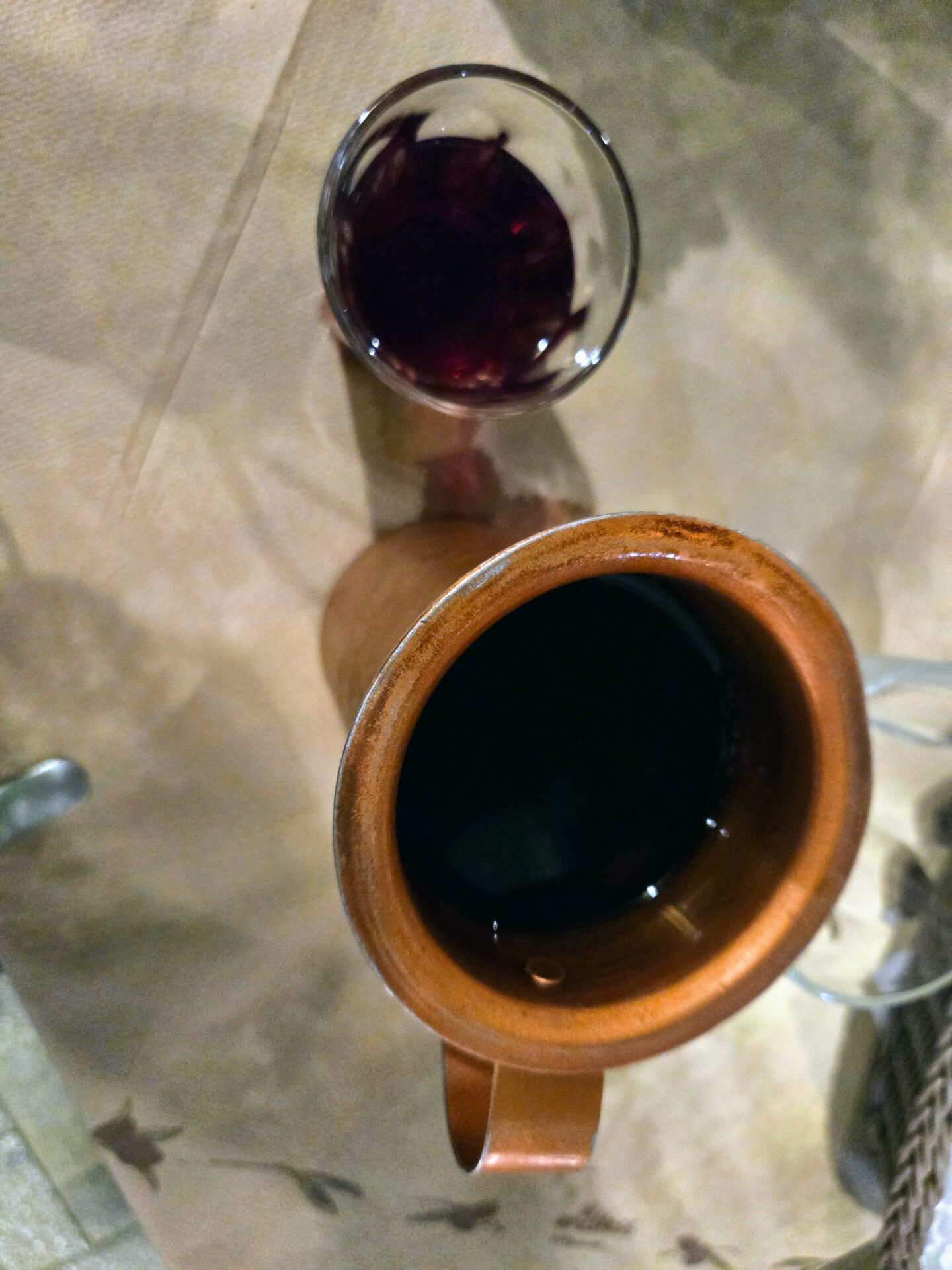 a glass of wine next to a brown pitcher
