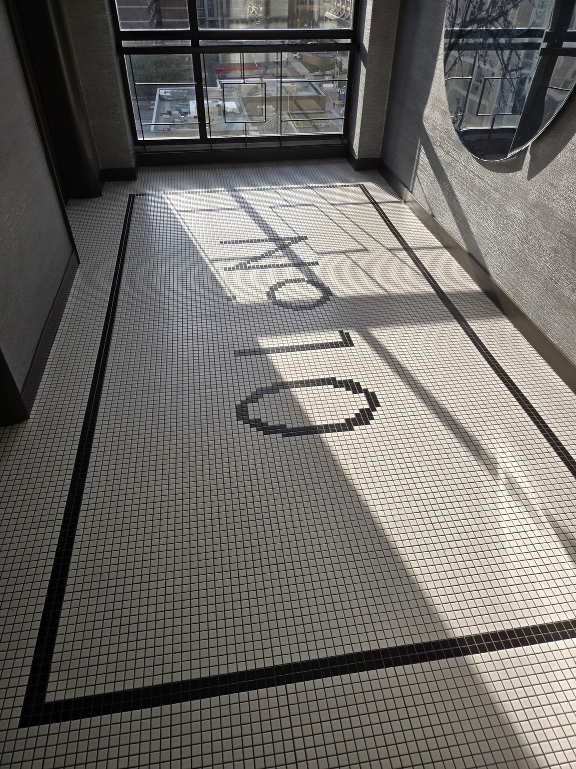 a black and white tiled floor with a circular mirror