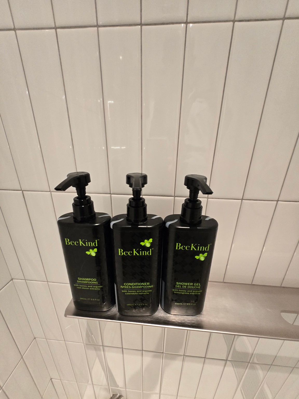 a group of black bottles with green text on a metal shelf