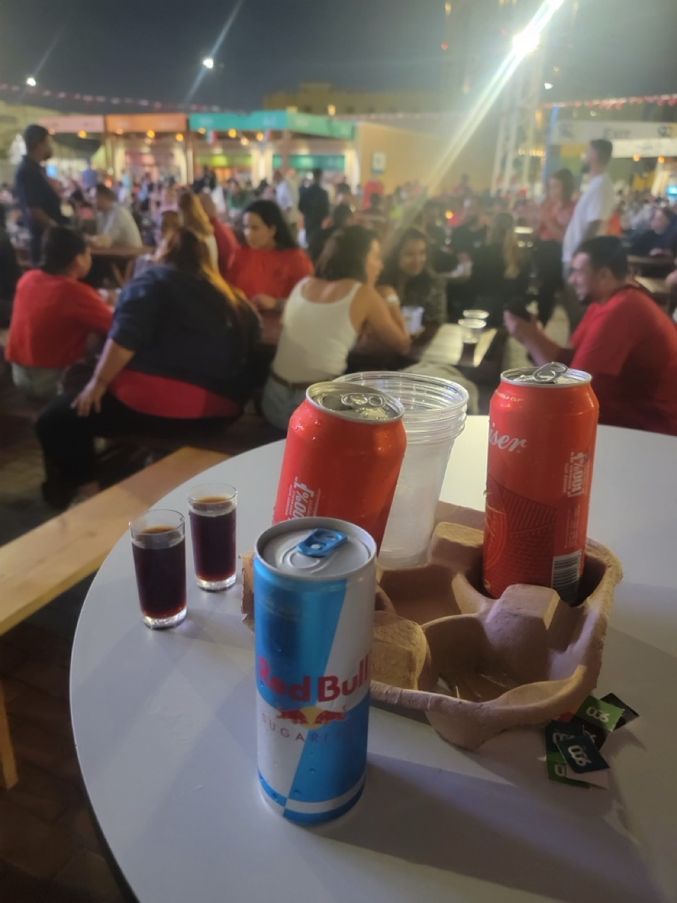 a group of people sitting at a table with drinks and cans