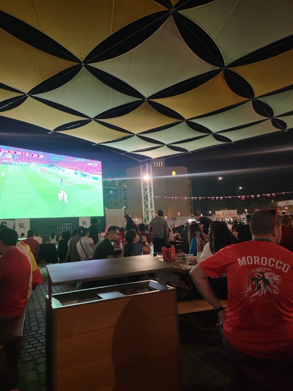 a group of people sitting at tables and watching a football game