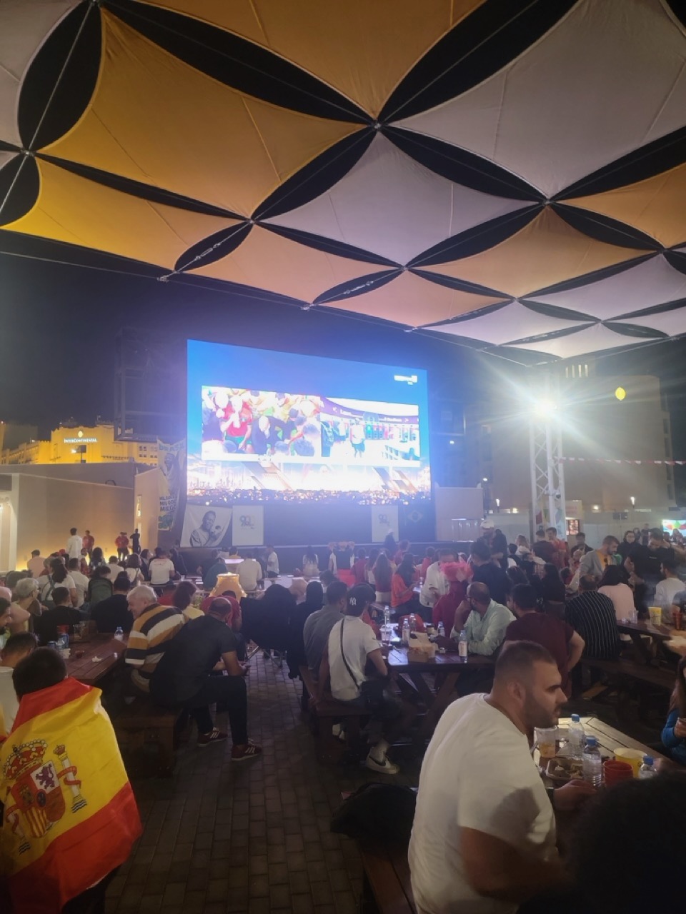 a large group of people sitting at tables and eating outdoors