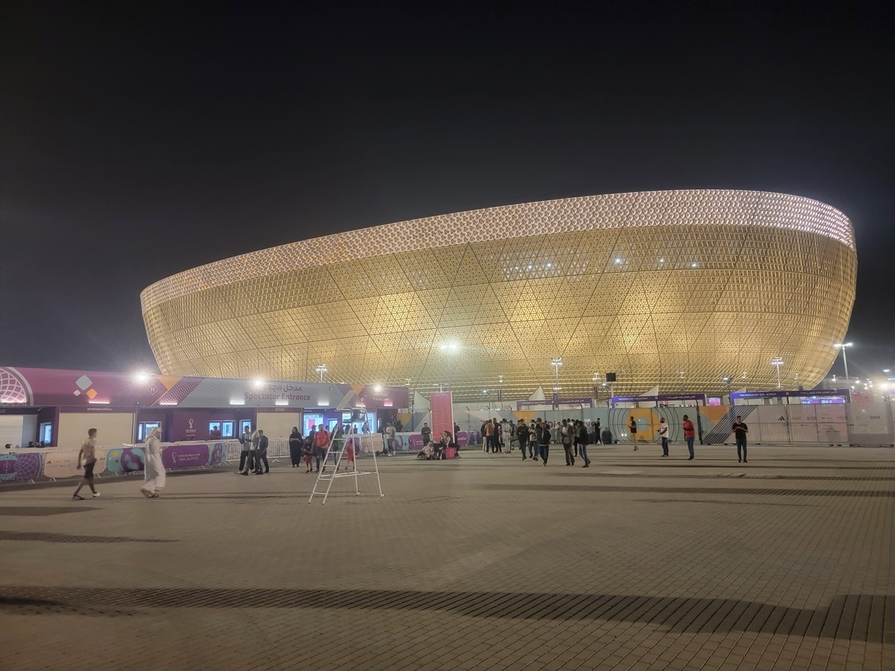 a large circular building with people walking around with Mercedes-Benz Superdome in the background