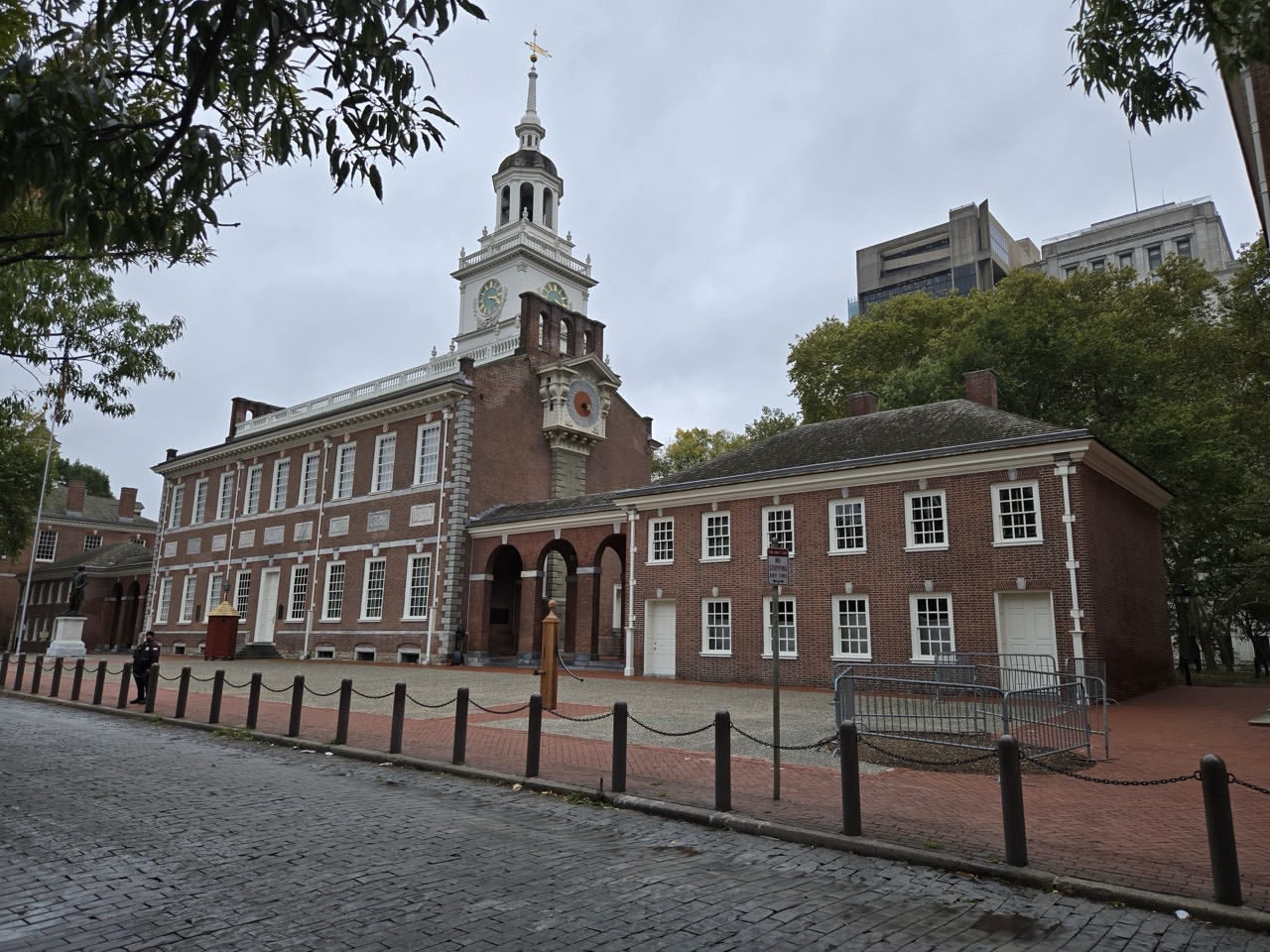 a brick building with a clock tower with Independence Hall in the background